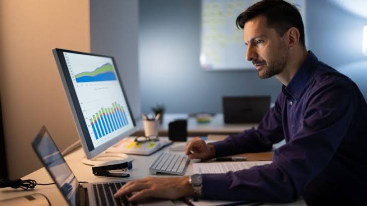 A professional employee analyzing data charts and digital software on dual monitors in a modern office for TechElvo.